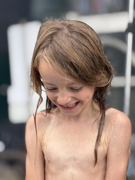 A young girl smiles while getting ready in the bathroom